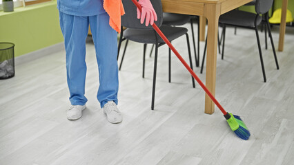 Fototapeta na wymiar Middle age woman professional cleaner cleaning floor at office