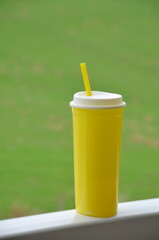 copo amarelo com canudo em fundo verde com espaço para texto, conceito de vida fitness e saúdavel 