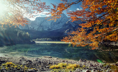 Awesome alpine highlands in sunny day. Scenic image of fairy-tale lake during sunset. Majestic Rocky Mountains on background. Wild area. Fusine lake. Italy, Julian Alps. Best travel locations.