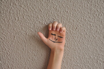 mão com rosto feliz , infância alegre , atividade de pintura infântil 