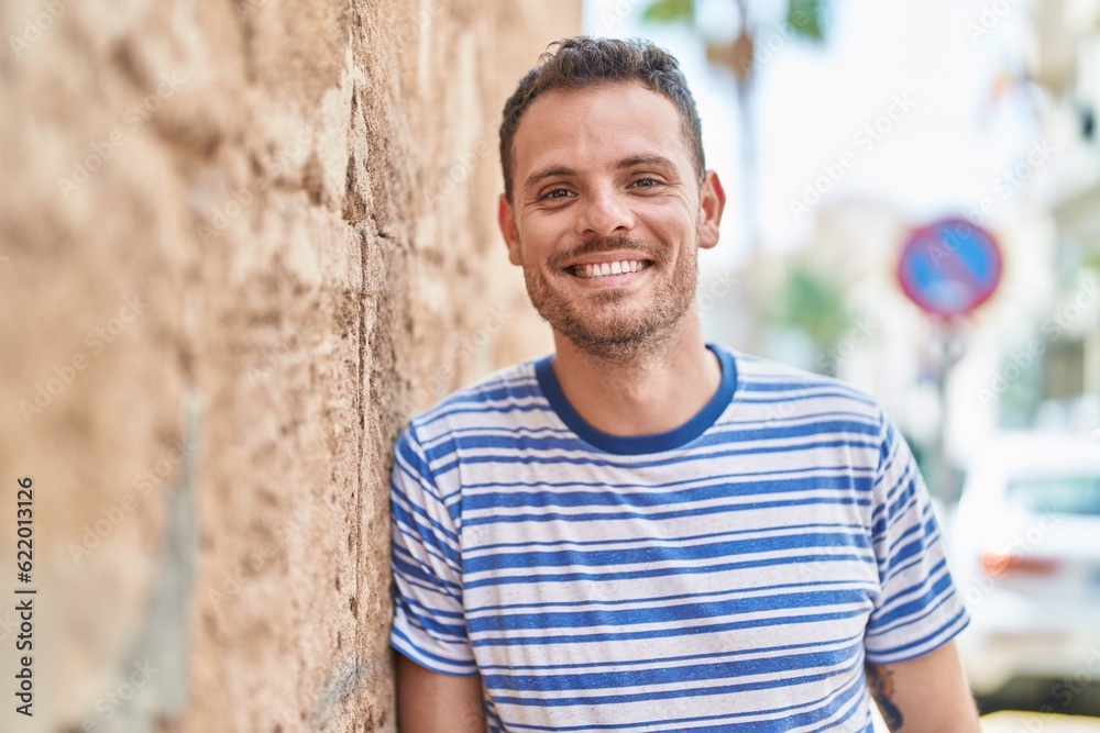 Wall mural young hispanic man smiling confident standing at street