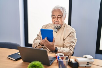 Middle age grey-haired man business worker using touchpad and laptop at office