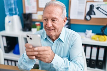 Obraz premium Middle age grey-haired man business worker using smartphone working at office