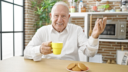 Senior grey-haired man having breakfast speaking at dinning room