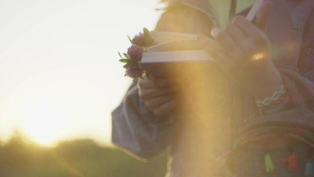 Beautiful Caucasian teenage girl reading a book in the garden at sunset. Education and self-development of the child. High quality 4k footage