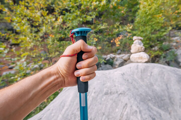 Hiking stick or pole in hand of a male traveler with scenic mountain valley in the background