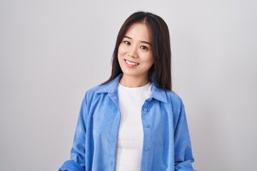 Fototapeta premium Young chinese woman standing over white background smiling cheerful with open arms as friendly welcome, positive and confident greetings