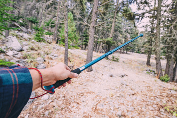 Hiking stick or pole in hand of a male traveler with scenic mountain valley in the background