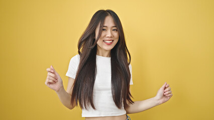 Young chinese woman smiling confident dancing over isolated yellow background