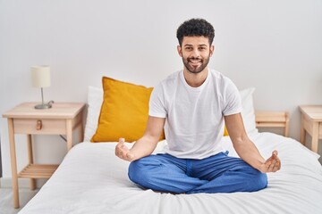 Young arab man doing yoga exercise sitting on bed at bedroom