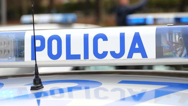 Poland, Polish police car blue lights flashing, vehicle top detail, closeup. Policja sign, symbol, nobody. National emergency services, crime prevention, public protection and first response concept