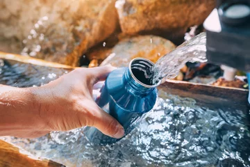 Fototapete Camping Pouring water from a spring source at camping or hiking. Clean looking water can be contaminated and dangerous to health