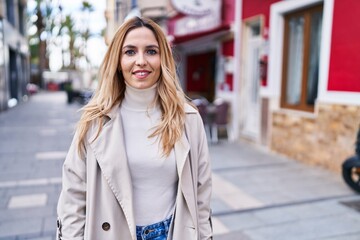 Young blonde woman smiling confident standing at street