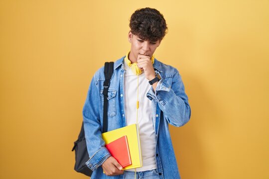 Hispanic teenager wearing student backpack and holding books feeling unwell and coughing as symptom for cold or bronchitis. health care concept.