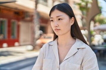 Fototapeta premium Chinese woman looking to the side with relaxed expression at street