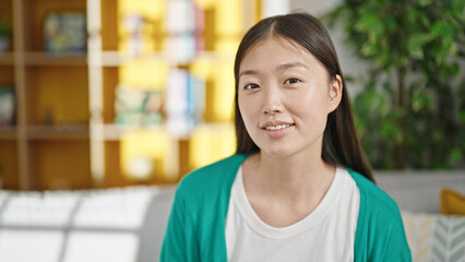 Young chinese woman smiling confident sitting on sofa at home