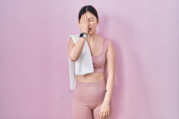 Chinese young woman wearing sportswear and towel yawning tired covering half face, eye and mouth...
