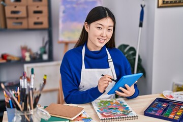 Chinese woman artist using touchpad drawing on notebook at art studio