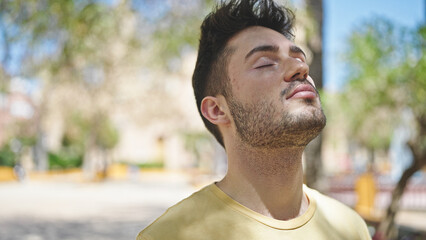 Young hispanic man breathing with closed eyes at park