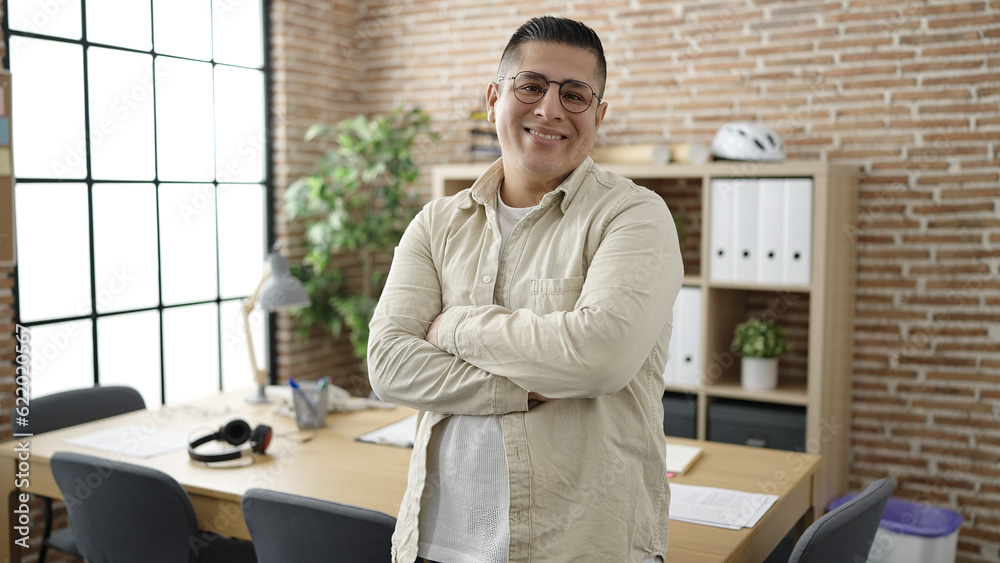 Sticker Young hispanic man business worker standing with arms crossed gesture at office