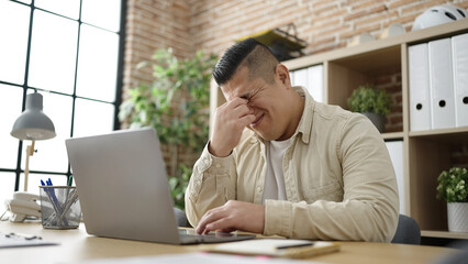 Fototapeta premium Young hispanic man business worker stressed using laptop at office