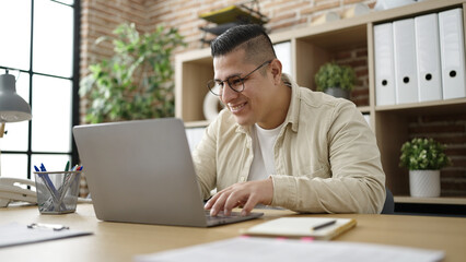 Young hispanic man business worker using laptop working at office