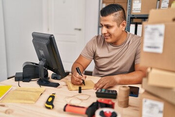 Young latin man ecommerce business worker writing on package at office