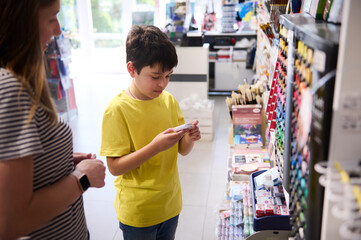 Adorable teenage boy choosing a modeling clay in a school stationery store. People. Creative hobby. Education. Fine art