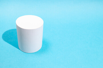 above view of hand-crafted paper cylinder on turquoise blue background with copyspace
