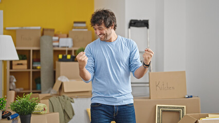 Young hispanic man smiling confident standing with winner gesture at new home