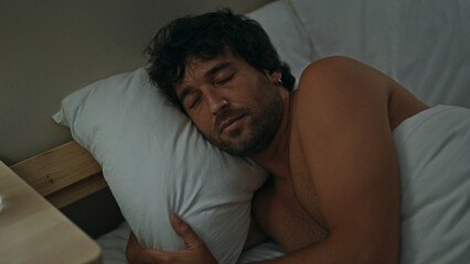 Young hispanic man lying on bed sleeping shirtless at bedroom