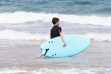 Young surfer takes surfboard to the ocean waves