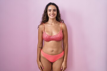 Fototapeta premium Young hispanic woman wearing lingerie over pink background with a happy and cool smile on face. lucky person.