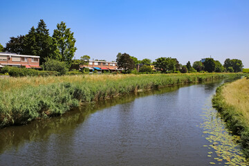 Fototapeta na wymiar Beautiful idyllic Aa river landscape on the outskirts of dutch city, waterfront homes - S-Hertogenbosch, Netherlands