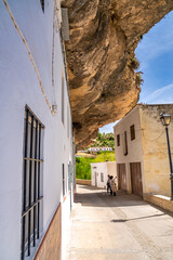 Setenil de las Bodegas, Spain - April 6, 2023: Typical Andalucian village with white houses and sreets with dwellings built into rock overhangs above Rio Trejo