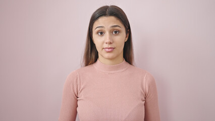 Young beautiful hispanic woman standing with serious expression saying no over isolated pink background