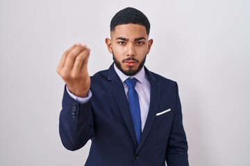 Young hispanic man wearing business suit and tie doing italian gesture with hand and fingers confident expression