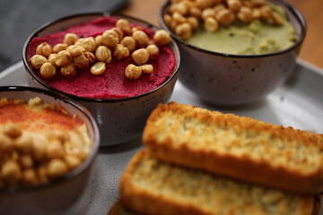 Uma festa de sabores: três tipos de homus de grão de bico, servidos com torradinhas crocantes, em um evento caprichado. 