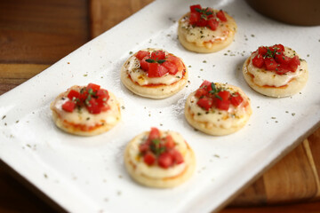 Deliciosas mini pizzas de queijo mussarela, tomates e manjericão, perfeitas para saborear em um evento especial.