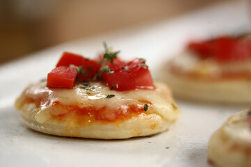Deliciosas mini pizzas de queijo mussarela, tomates e manjericão, perfeitas para saborear em um evento especial.