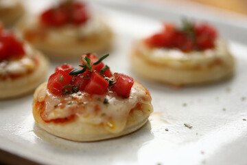 Deliciosas mini pizzas de queijo mussarela, tomates e manjericão, perfeitas para saborear em um evento especial.