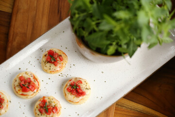 Deliciosas mini pizzas de queijo mussarela, tomates e manjericão, perfeitas para saborear em um evento especial.