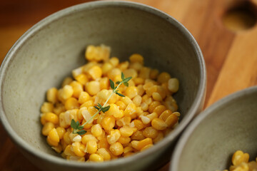 Milho verde fresco e apetitoso, servido em uma pequena travessa e decorado com um ramo de tomilho, em um evento de café da manhã.
