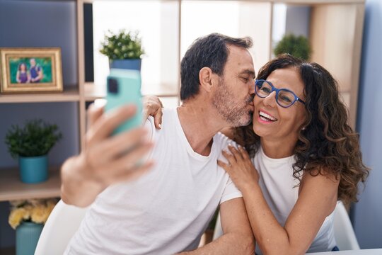 Man and woman couple make selfie by smartphone sitting on table at home
