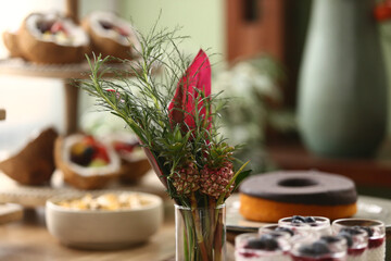 Um encantador arranjo floral com flores em tons de rosa e pequenos abacaxis decorativos, criando uma atmosfera vibrante em uma mesa de evento.