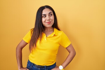 Obraz premium Young arab woman standing over yellow background smiling looking to the side and staring away thinking.