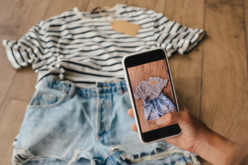 Woman taking picture of used clothes. Selling used clothes concept. - obrazy, fototapety, plakaty