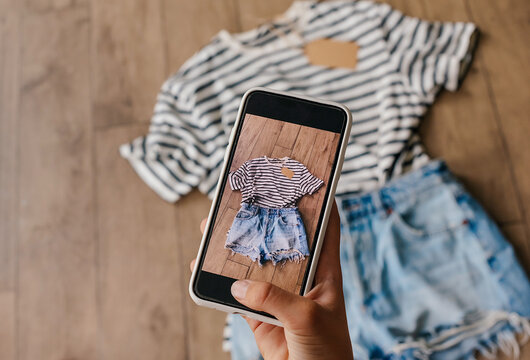 Woman taking picture of used clothes. Selling used clothes concept.