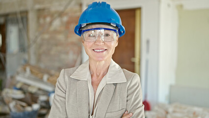 Middle age blonde woman architect smiling confident standing with arms crossed gesture at construction site