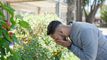 Young hispanic man with pollen allergy sneezing at park
